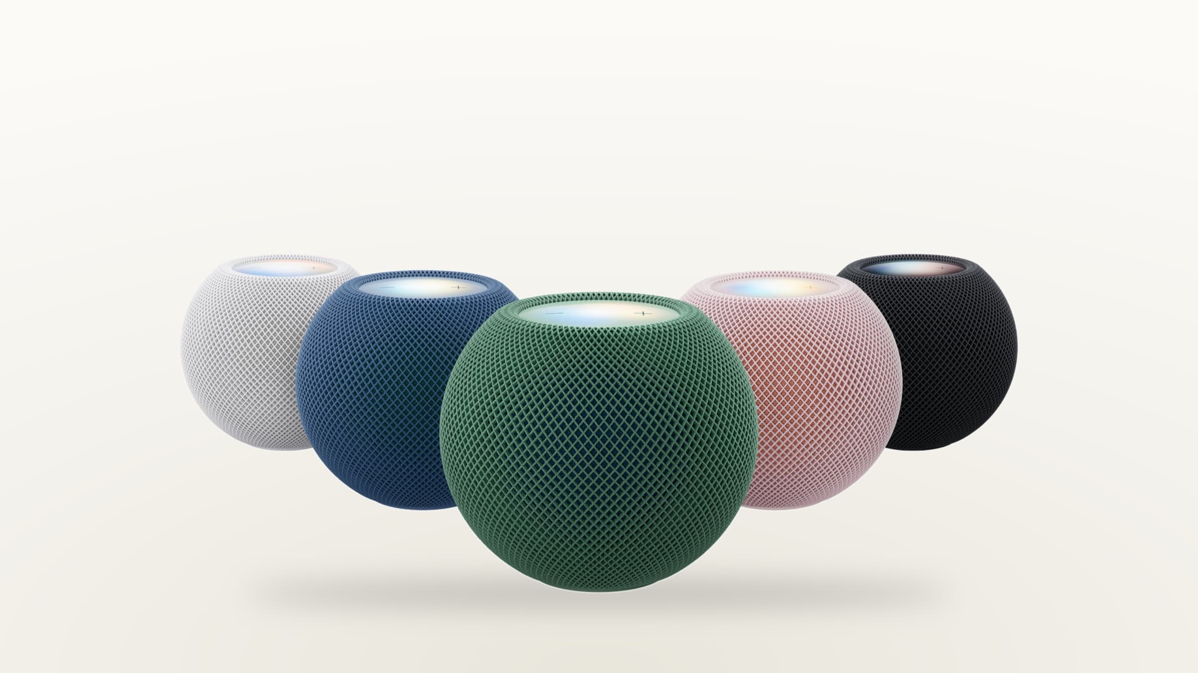 HomePod mini 2 in white, blue, green, pink and midnight with glowing tops on a light background