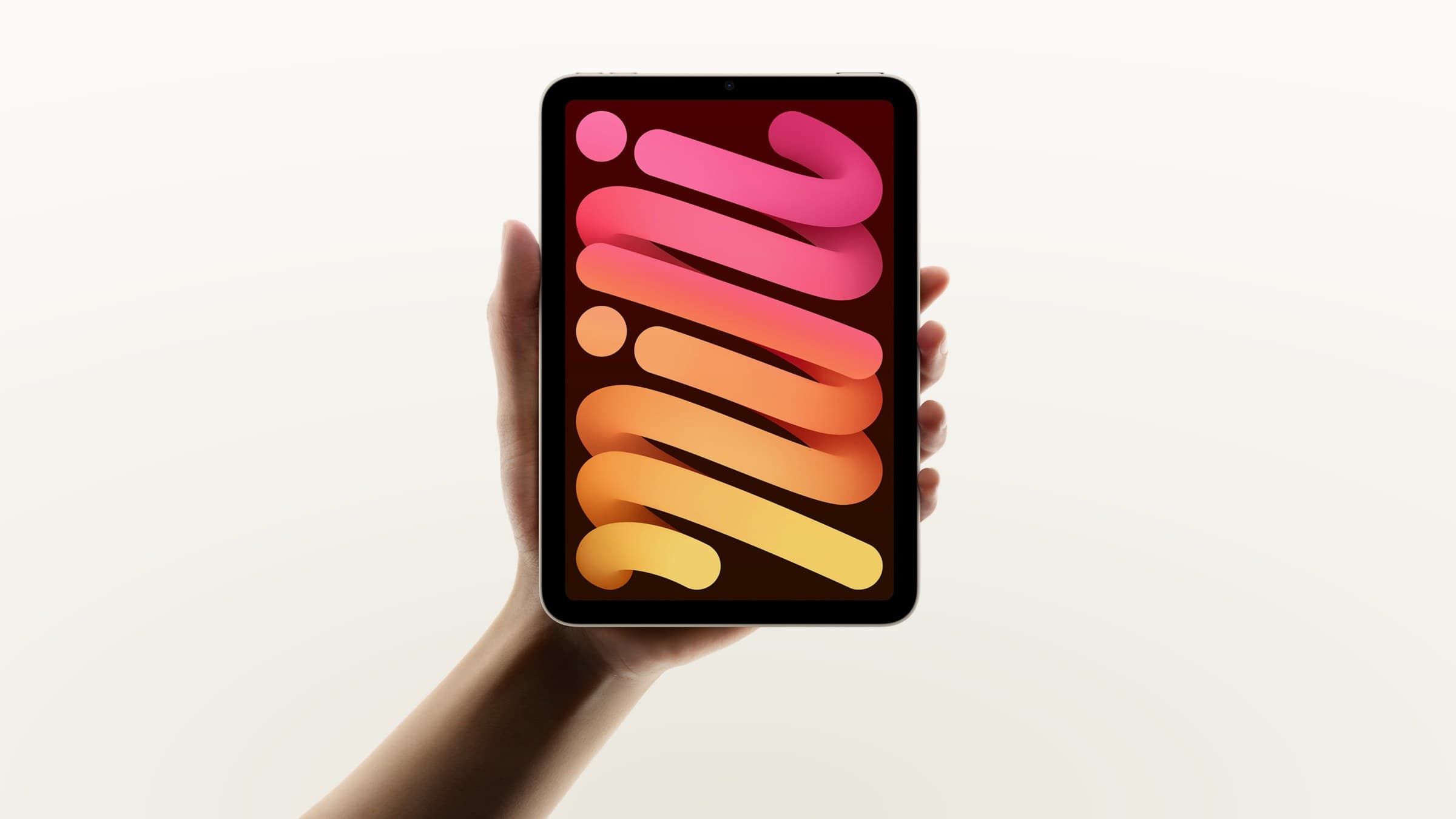 Current iPad mini held in one hand, on a light gradient background