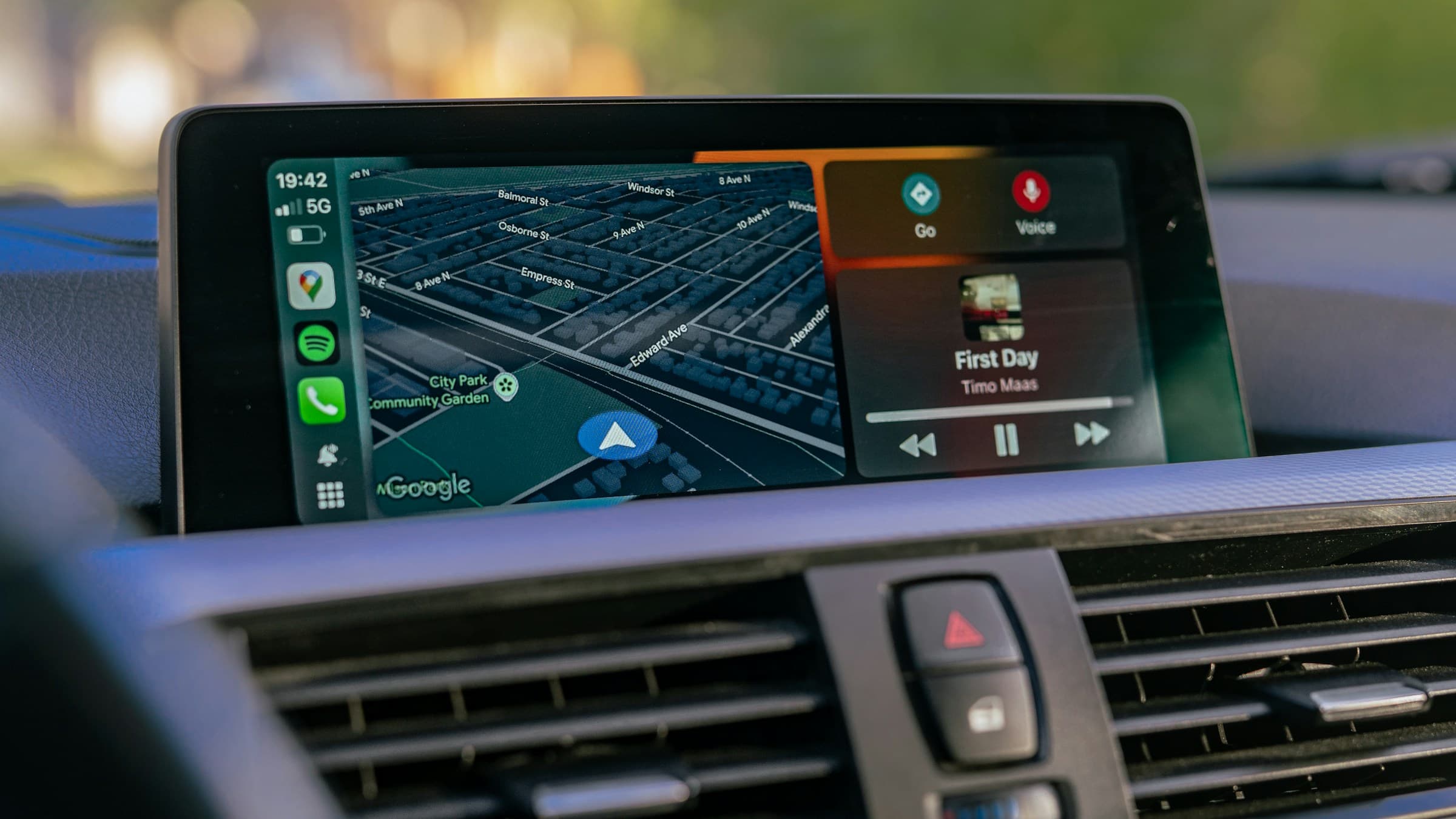 Car dashboard screen showing CarPlay with navigation and music