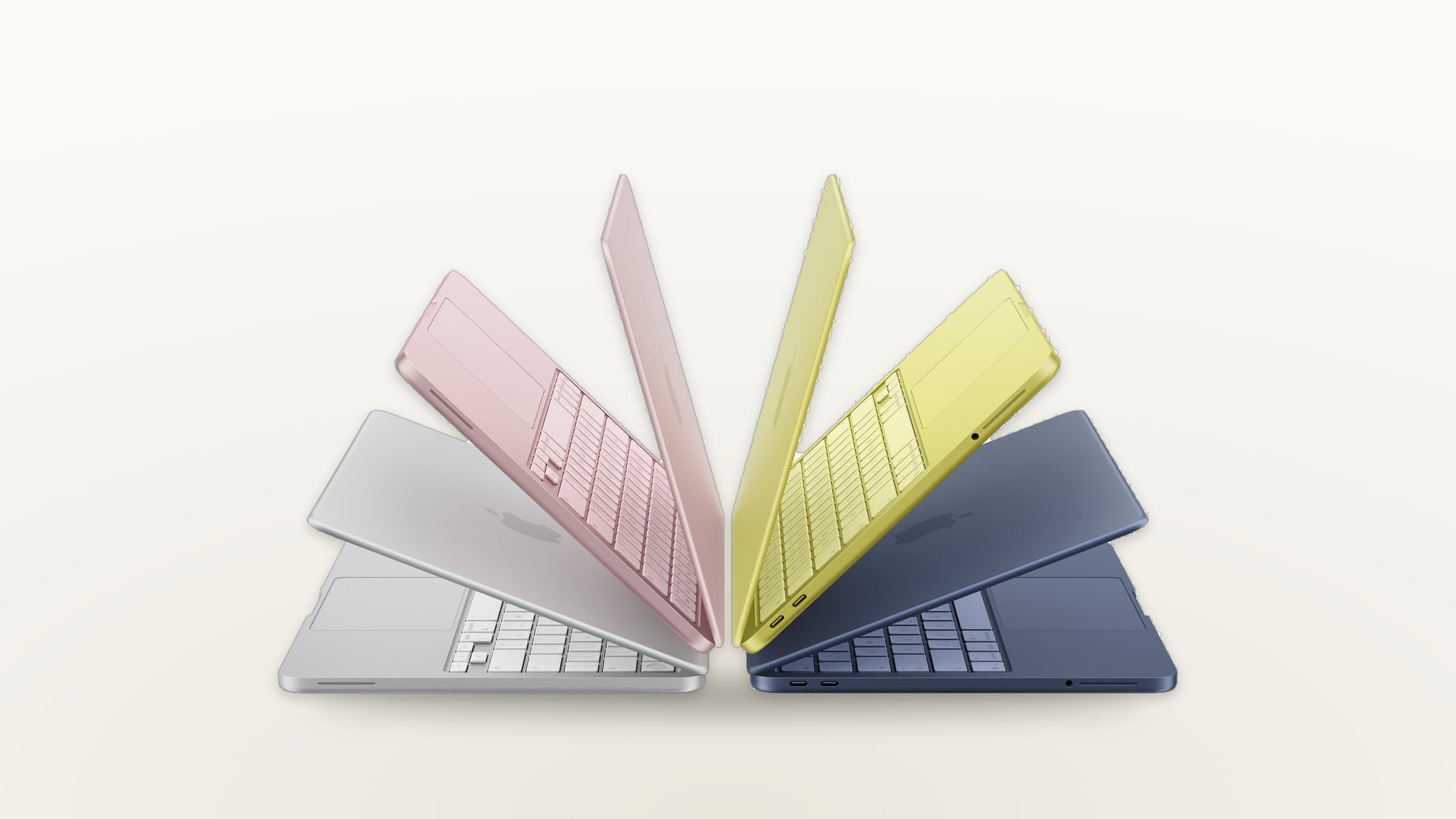MacBook Neo in silver, blush, citrus and indigo fanned out on a light gradient background